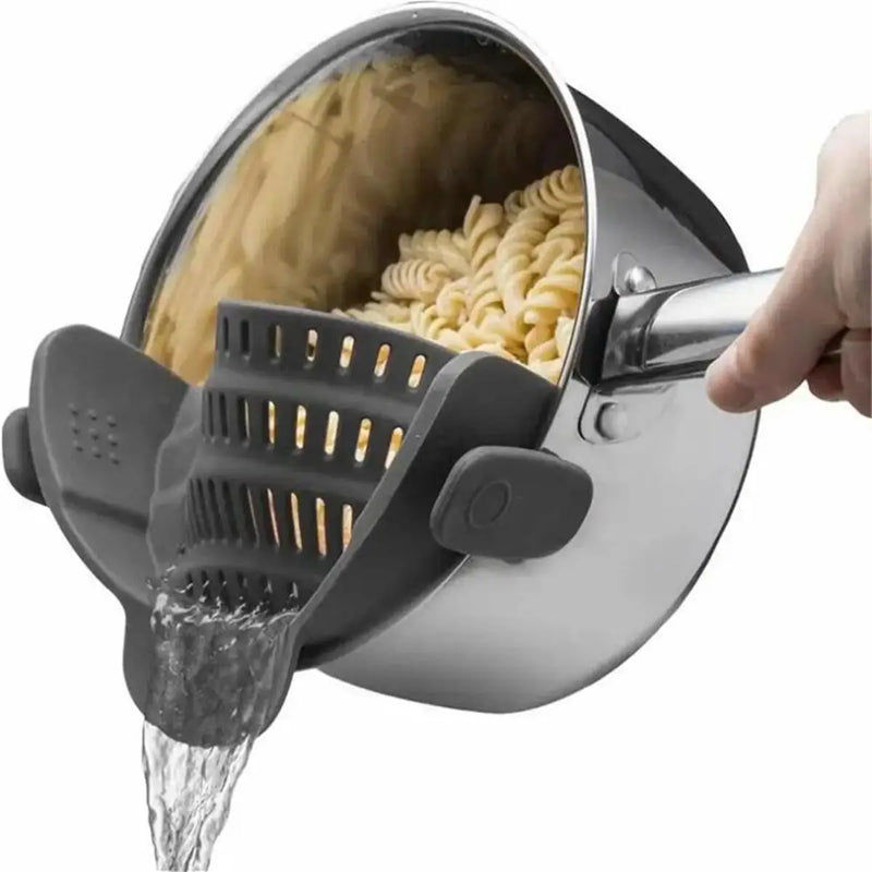 Escorredor de macarrão com clipe ajustável encaixado em panela de inox escorrendo água quente de forma prática e segura.
