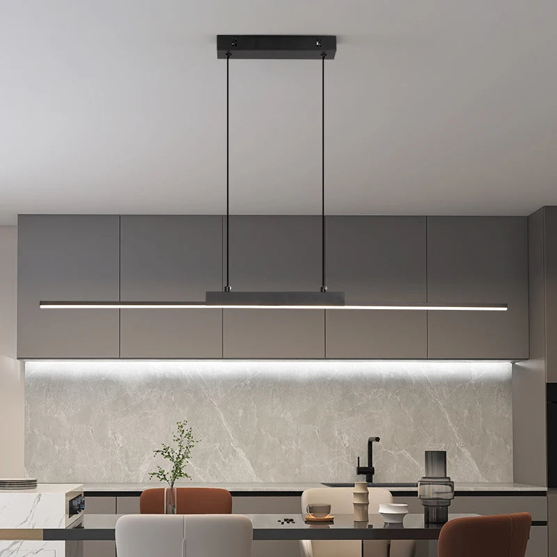 Lustre pendente LED linear moderno preto instalado sobre bancada de cozinha, com iluminação uniforme e design minimalista.