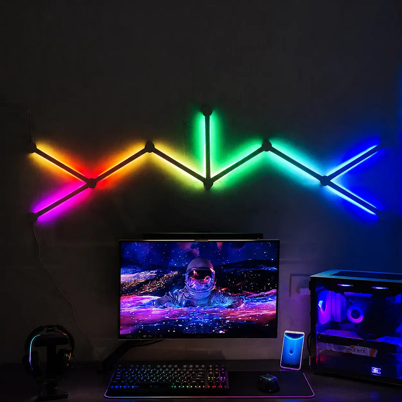 Luminária LED RGB inteligente modular instalada na parede com iluminação colorida em setup gamer com monitor e computador.