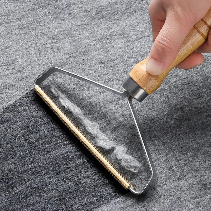 Removedor manual de pelos e fiapos com cabo de madeira e lâmina metálica, ideal para limpar roupas, sofás, tapetes e estofados.