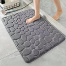 Tapete antiderrapante super absorvente cinza para banheiro com relevo em formato de pedras, ideal para secagem rápida e maior segurança.