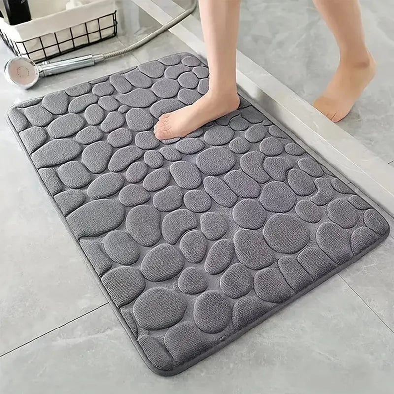Tapete antiderrapante super absorvente cinza para banheiro com relevo em formato de pedras, ideal para secagem rápida e maior segurança.